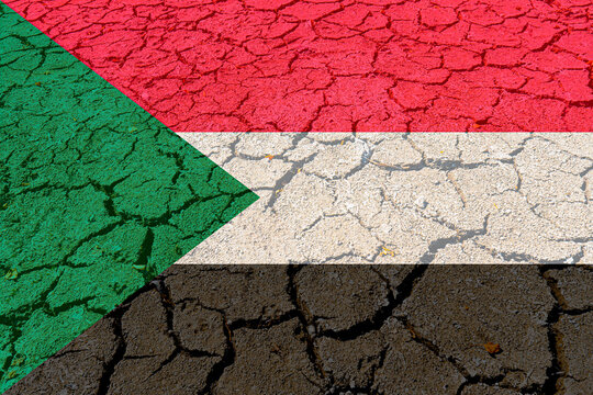 Cracked clay lake bed with Sudanese flag painted on it (close-up). Concept of climate change, drought and drying up of water bodies in Sudan
