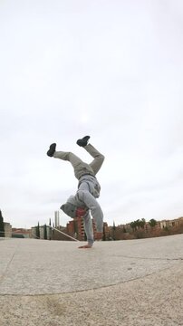 Breakdancer performing handstand freeze in urban environment