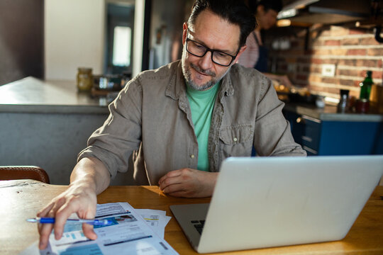 Stressed man managing finances and bills at home on laptop