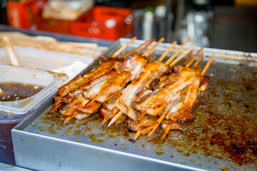 Street food, a hearty bacon kebab with sauce, grilled on a barbecue