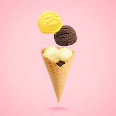 Ice cream scoops and waffle cone in air on pink background