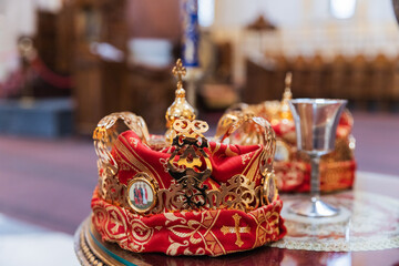 Ornate Golden Crowns Adorned With Crosses Rest on a Glass Table Within a Majestic Orthodox Church Interior