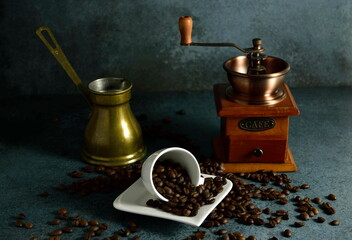 Coffee grinder, coffee beans, pot and espresso cup.