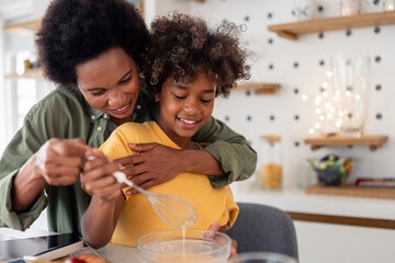 Playful African Mother and Daughter Sharing a Fun Cooking Moment in a Bright Modern Kitchen