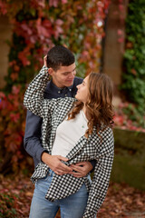 Fototapeta premium Young Cute Female Hugs Boyfriend. In Autumn Outdoor. Lovers Walking in Park. Attractive Funny Couple. Lovestory in Forest. Man and Woman. Cute Lovers in the Park. Family Concept. Happy Couple.