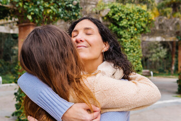 Fototapeta premium Two smiling women sharing a tender hug in a park