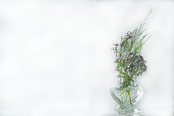 On white background a small bouquet in a transparent glass vase shaped like a heart