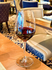 Glass of red wine on a table in the bar of a hotel. No people.