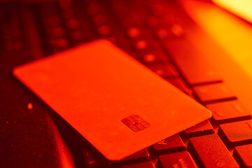 Glowing red credit card resting on laptop keyboard, representing digital financial transactions and cybersecurity challenges