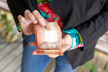 Businesswoman's hands gripping chilean peso banknotes, highlighting professional financial handling and monetary wealth in corporate environment