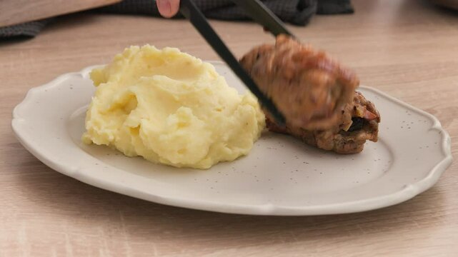 cook put roasted chicken meat rolls on plate with nashed potatoes for making delicious healthy meal, food closeup