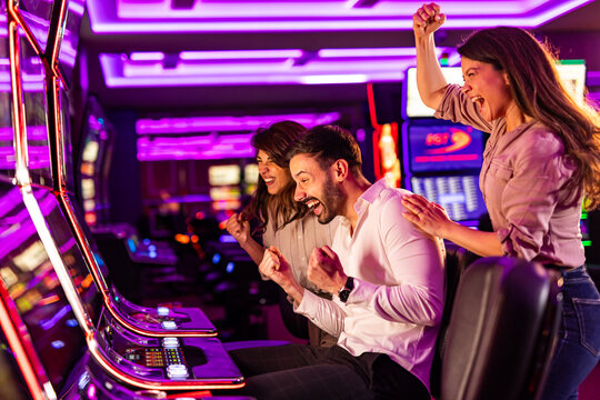 Friends Celebrating a Win at Slot Machines in a Vibrant Casino Setting