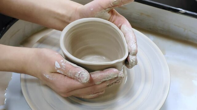 Child making ceramic vase on rotating pottery wheel at workshop. Creativity and traditional crafts concept. 