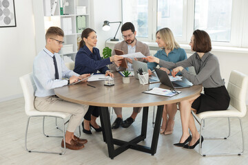 Coworkers working together at wooden table in office