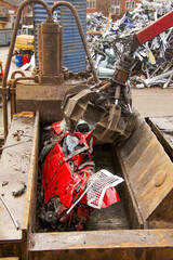 Cars getting crushed and demolished at wrecking junk yard. Car in crushing machine.