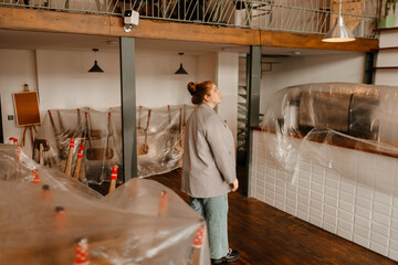 The female owner is standing and looking up, preparing for the opening of the cafe