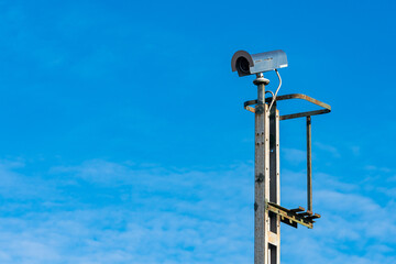 Security camera on pole against clear blue sky