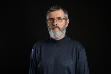 Naklejka premium Portrait of mature man in glasses on black background