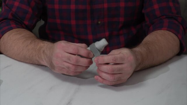 the male person holds a plastic finger brace in his hands and shows its Velcro fastening. a device to ensure immobility