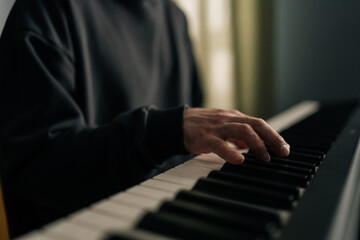 Obraz premium Close-up view of musician hands skillfully playing synthesizer in cozy home studio, crafting melodies and enjoying creative process in personal and inviting space. Concept of recording music at home.