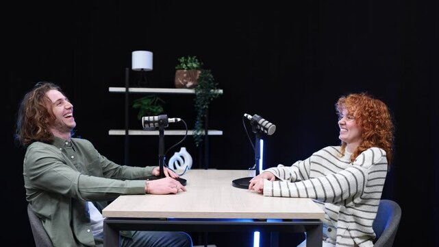 Podcasters laughing during recording session in studio