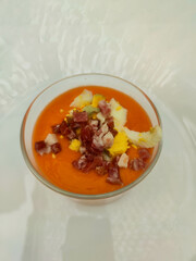 Traditional Andalusian salmorejo served in a clear glass with boiled egg and chopped ham