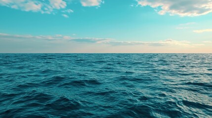 Obraz premium The tranquil blue ocean stretches out to the horizon, bathed in soft sunlight as fluffy clouds drift lazily above. The moment evokes a sense of peace and wonder.