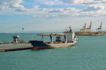 Cargo Ship Docked at Port with Yellow Gantry Cranes and Turquoise Water