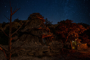 Traditional shepherd hut (ovile) in the Supramonte mountains of Sardinia, Italy, illuminated at night under a starry sky in a wild and remote rural landscape. Baunei, Ogliastra, Nuoro, Sardinia, Italy