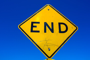 Yellow Road sign marking End of the Road in front of blue sky