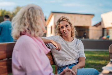Daughter smiling and talking with senior mother outdoors in backyard garden