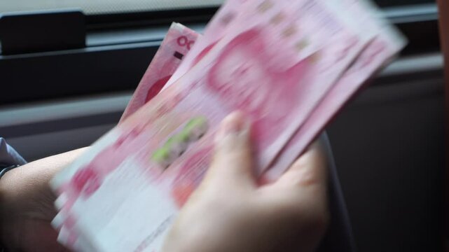 Counting cash money one hundred Chinese yuan bills, yuan banknotes Chinese currency (Renminbi or RMB) featuring 100-yuan banknote with Mao Zedong's for goods services, Cash on car