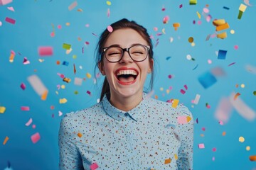 A cheerful woman laughing and smiling in the air amidst vivid colorful confetti, signifying joy, celebration, success and a festive mood.