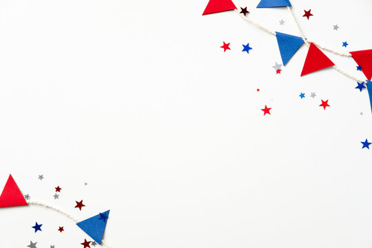 Patriotic festive decor with red and blue triangular flags, star-shaped confetti on a white background. Perfect for holidays, celebrations, or themed parties