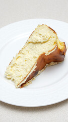 Close-up of a slice of San Sebastian cheesecake with caramel crust on a white plate.