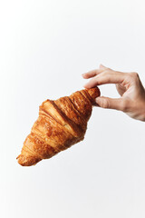 Hand holding croissant on white background, croissant in middle of hand