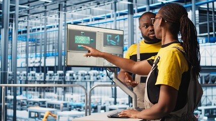 System administrators in smart factory collecting and analyzing data. Coworkers doing brainstorming, using tracking software in industrial plant equipped with advanced sensors, camera A close up