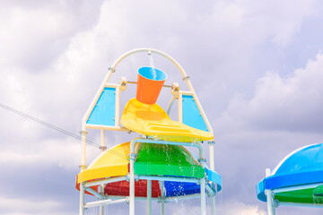 A colorful water slide with a bucket of water pouring out of it