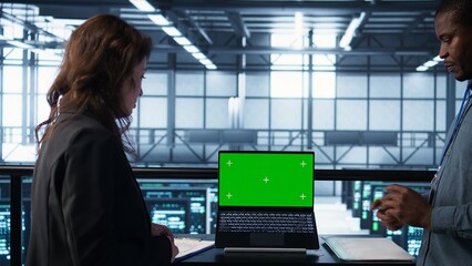 Coworkers in data center using mockup laptop, integrating green technologies. IT experts in server room using chroma key notebook to implement sustainable energy solutions, camera B close up