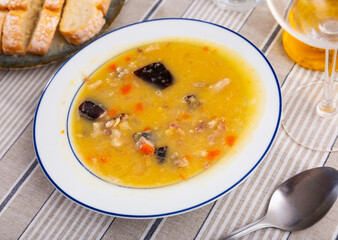 delicious pea soup with smoked meats and orange carrots cools down in white ceramic plate