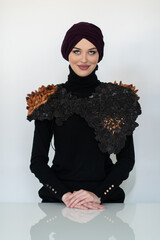 A stylish Muslim woman in a hijab presents her innovative handmade fashion accessory crafted from...