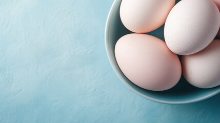 This image showcases classic white eggs placed in a stylish light blue bowl, expressing modernity alongside simplicity for culinary uses and aesthetic appeal.