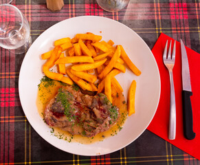 .On plate is large piece of fried veal with potatoes, sprinkled with herbs and coarse sea salt