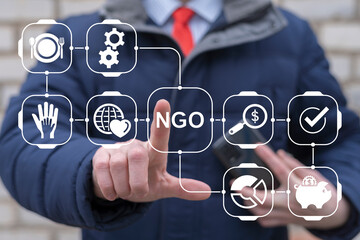 Business person or politician using virtual touch screen push abbreviation: NGO. NGO Non...