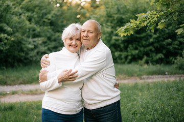 28.09.24 Vinnitsa, Ukraine: a nice couple of grandparents who look good and pose for a photo in light clothes in front of a park