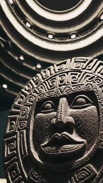 Ancient Aztec stone artifact displayed under museum lighting with a circular ceiling above. A tribute to Mesoamerican culture.