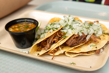 Birria tacos with cheese, fresh onion, and Mexican salsa, presented on a platter