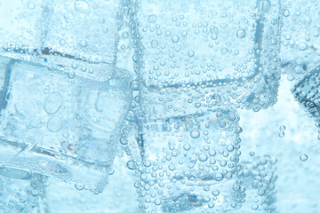 Refreshing soda water with ice cubes as background, closeup