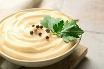 Delicious mayonnaise sauce with parsley and peppercorns in bowl on light table, closeup