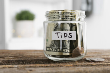 Glass jar with tips on wooden table indoors, closeup. Space for text
